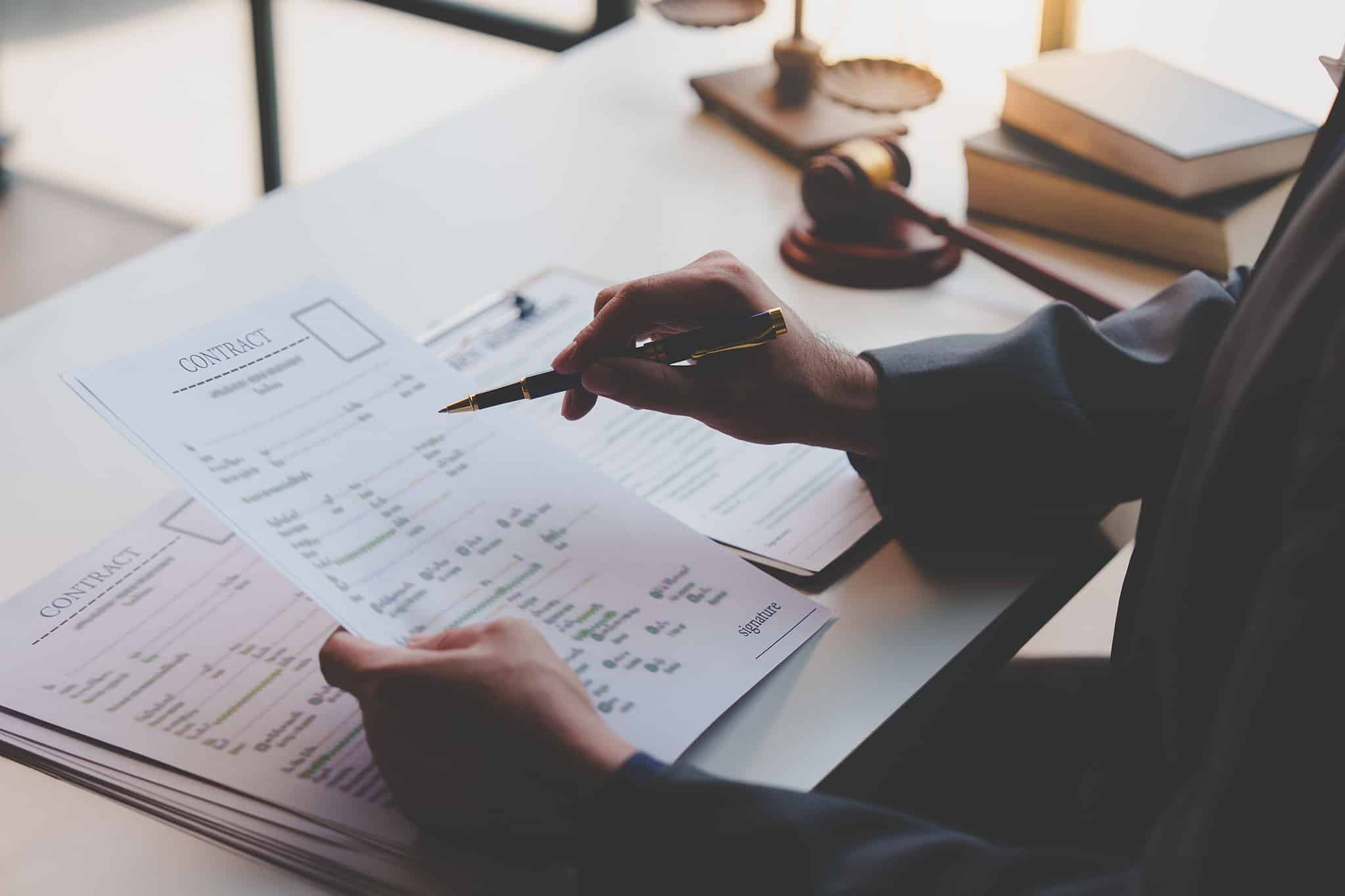 Person prüft Vertrag am Schreibtisch, markiert Stellen; Symbole für legale Steuergestaltung, Kanzlei München.