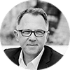 Schwarz-weiß-Porträt eines Mannes mittleren Alters mit Brille im Anzug, seitlichem Blick, unscharfer Hintergrund. Steuerberatung Unterföhring.