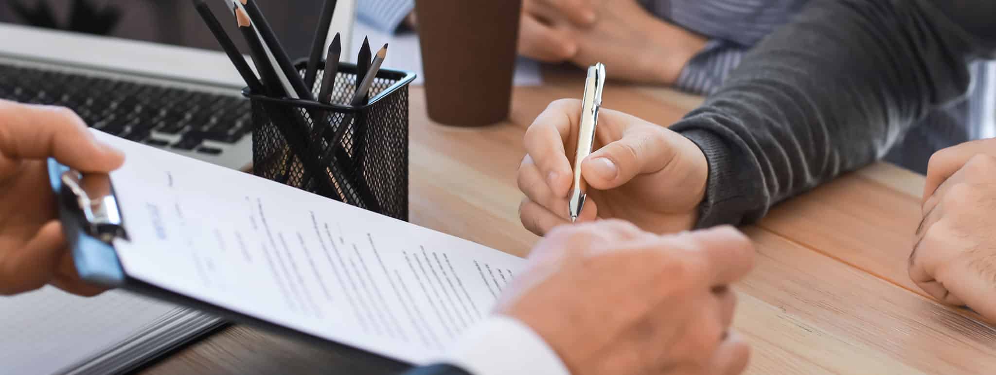 Zwei Personen unterzeichnen Nachlassplanungsdokumente am Schreibtisch in München; Lkm GmbH Rechtsanwälte & Steuerberater.