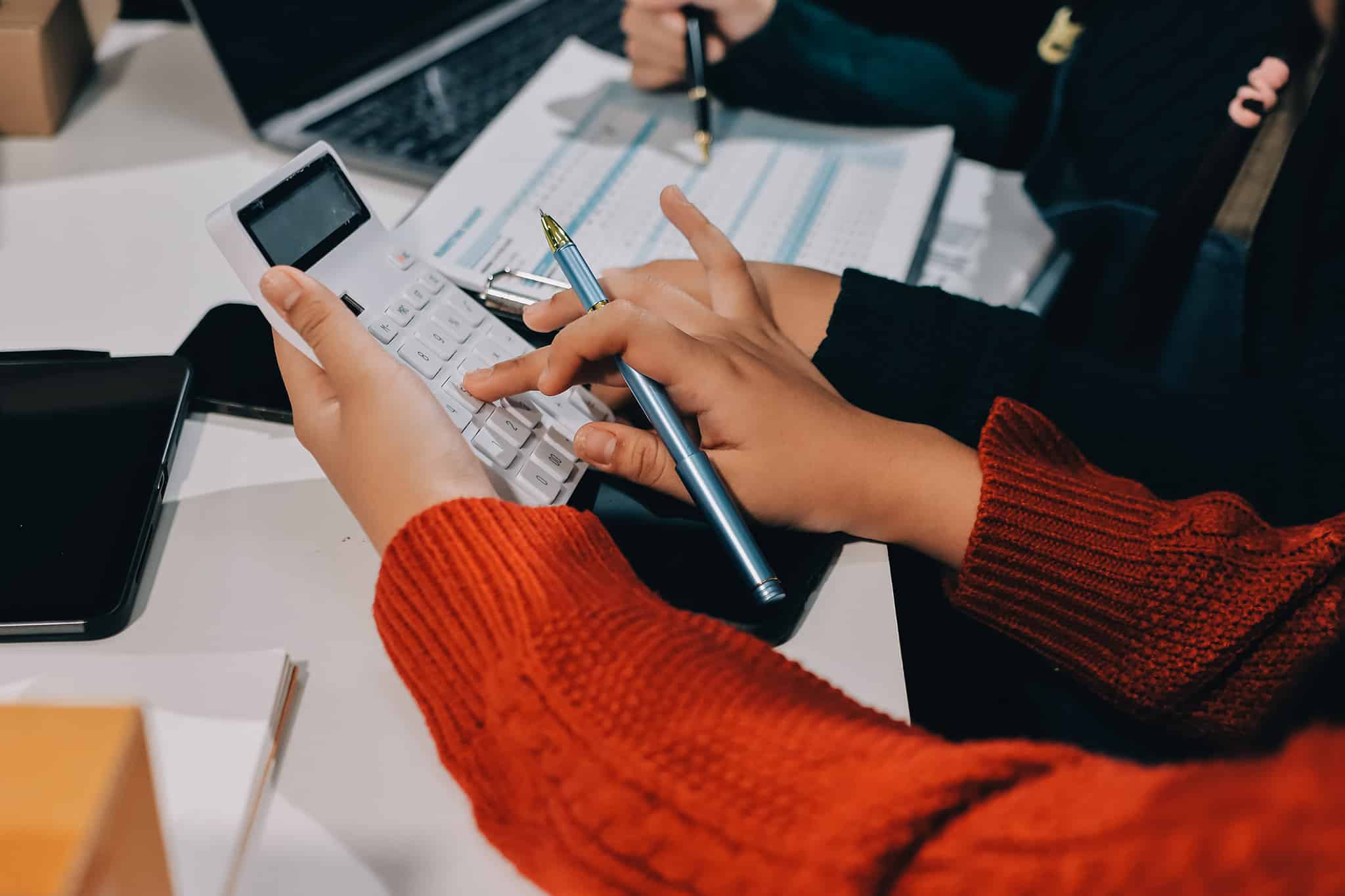 Zwei Personen besprechen Umsatzgrenzen mit Taschenrechner und Unterlagen, Steuerberatung bei Lkm GmbH Rechtsanwälte & Steuerberater.