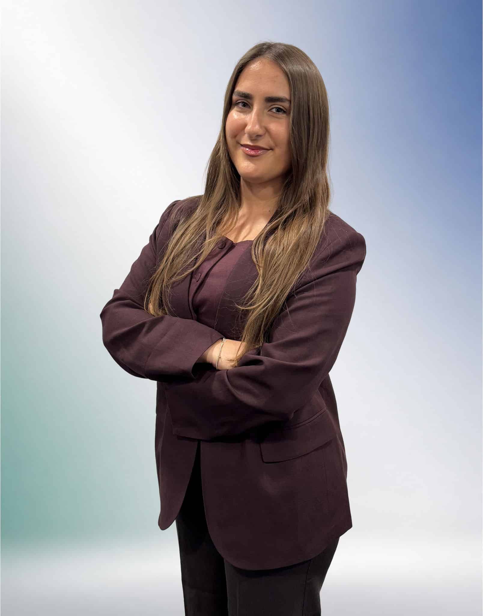 Frau mit langen braunen Haaren im Businessanzug vor einem grün-blauen Farbverlauf, Symbol für die Steuerberatung Unterföhring.