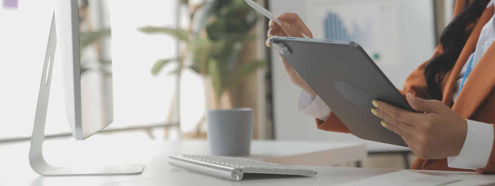 Person am Schreibtisch mit Tablet bei Online-Beratung in München, zeigt Digitalisierung bei Lkm GmbH Steuerberatung.