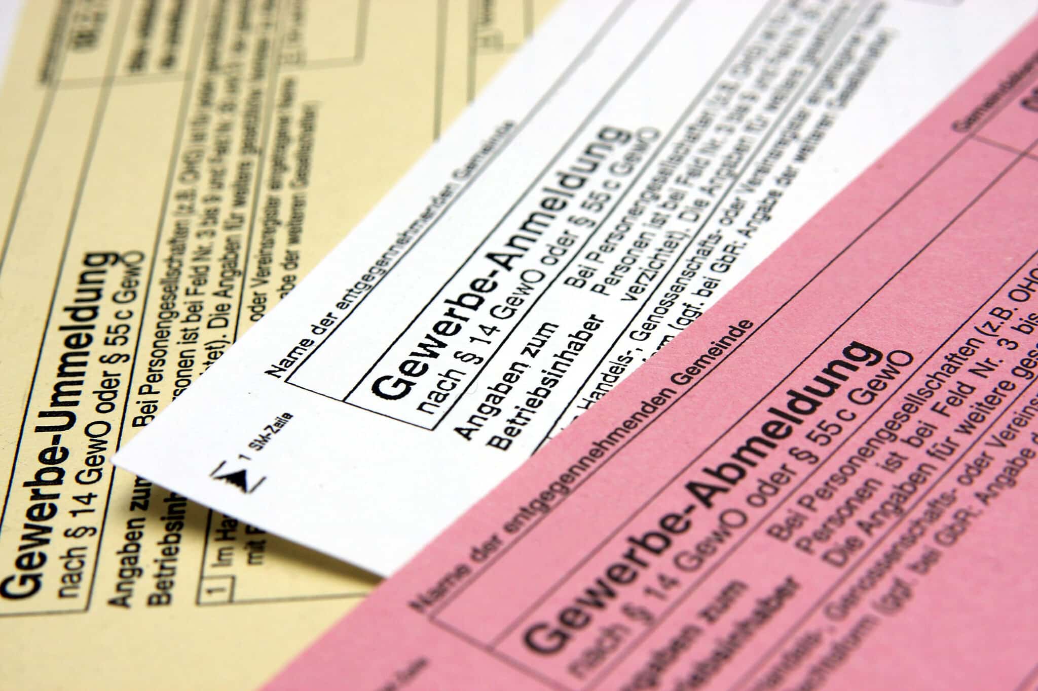 Drei ausgefüllte Gewerbeformulare auf Schreibtisch, wichtig für Scheinselbstständigkeit vermeiden, Lkm GmbH Steuerberatung.