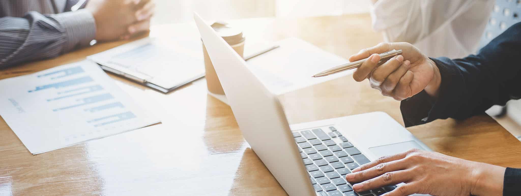 Team der Lkm GmbH bespricht am Tisch mit Laptop und Charts Finanzunterlagen, Schwerpunkt Steuerberatung in München.