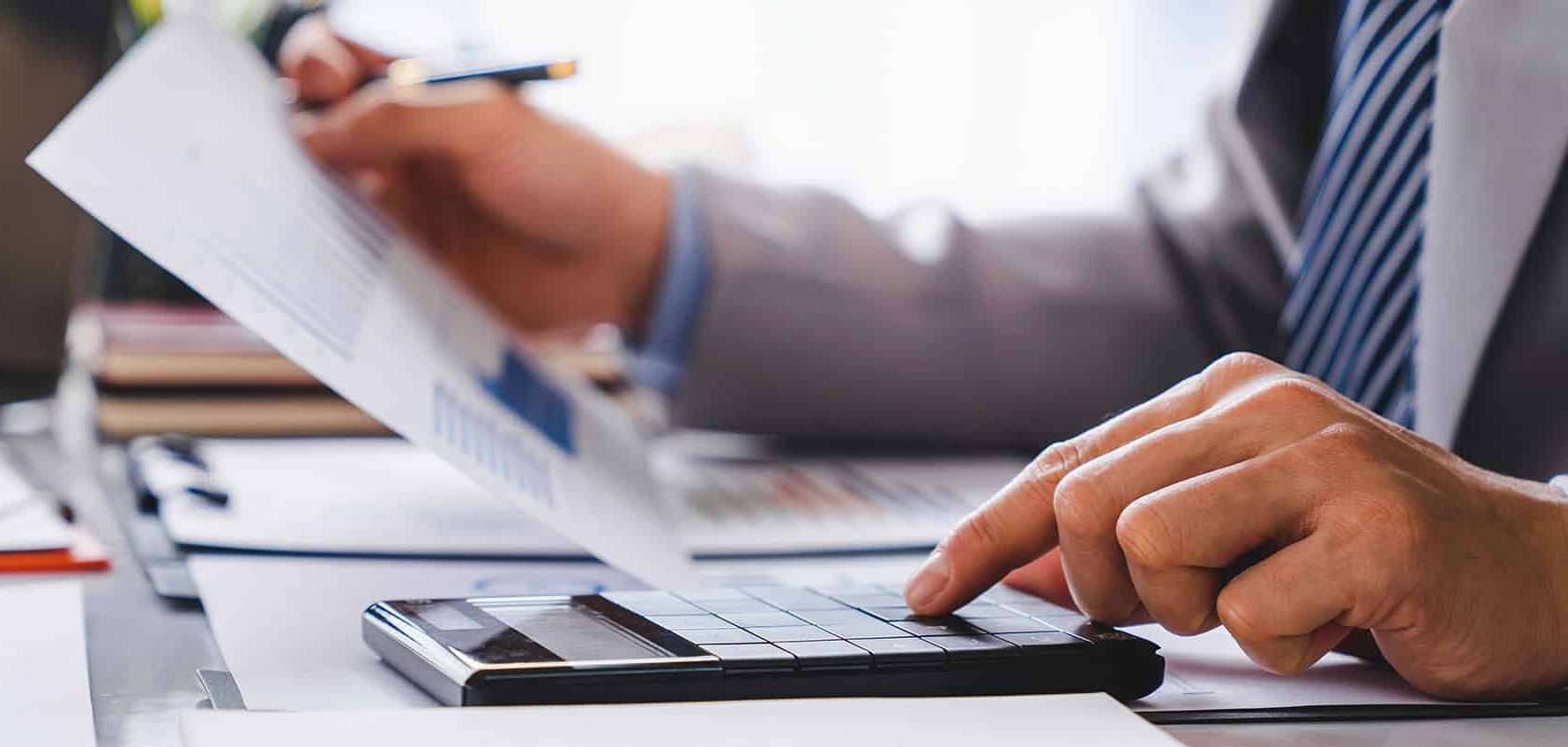 Im modernen Büro prüft eine Person Finanzdaten zu Wegzug 2026 per Taschenrechner, Lkm GmbH Steuerberatung.